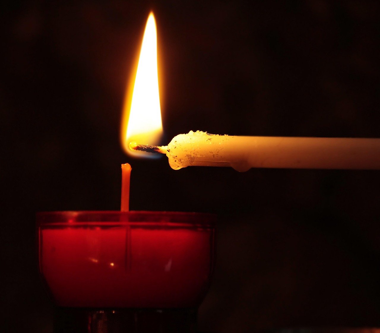 Grieving hand holds church candle, seeking solace.