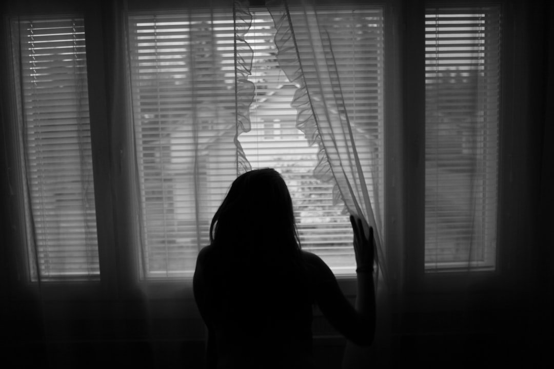 Woman silhouette by window, finding closure after abuse.