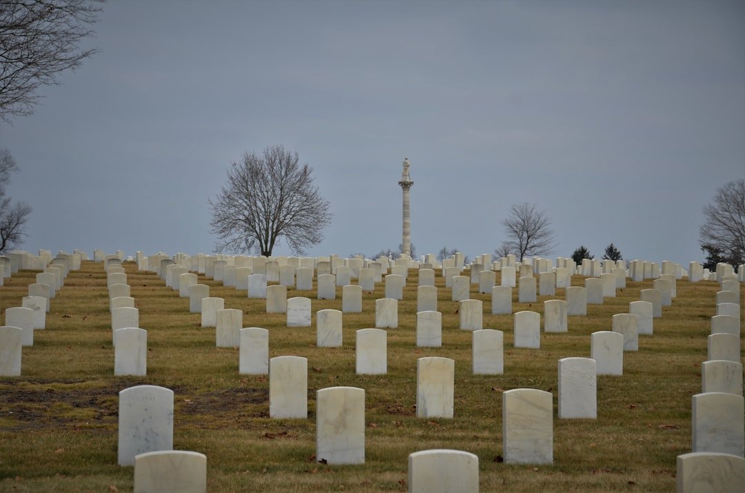 Cemetery with headstones and trees, military funeral.