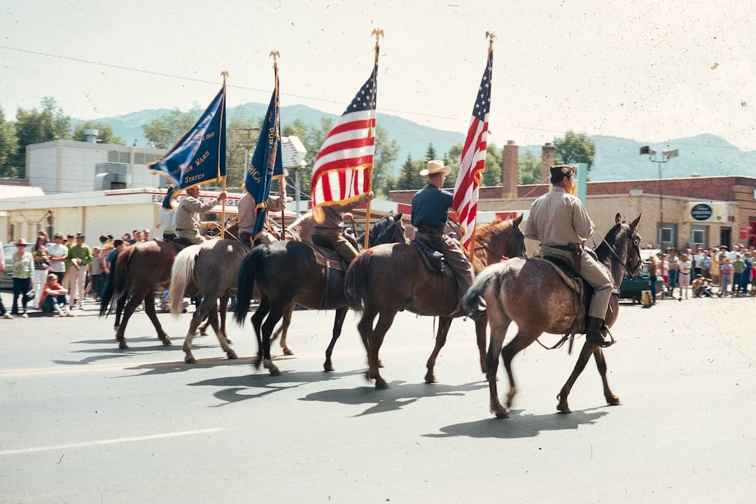 Military funeral parade, flags, riders on horseback, farewell.